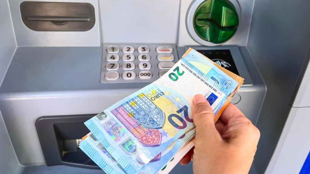Persona sacando dinero en efectivo de un cajero automático con billetes de euro