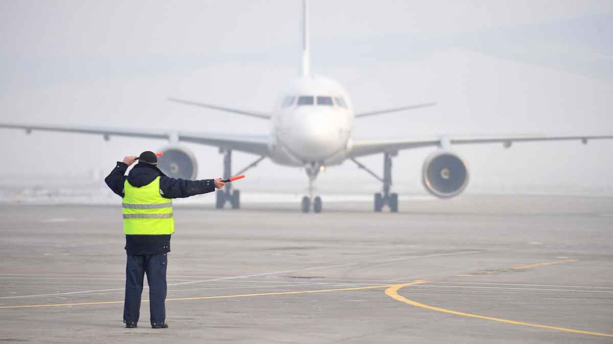 Trabajador de Aena señalizando un avión en pista del aeropuerto