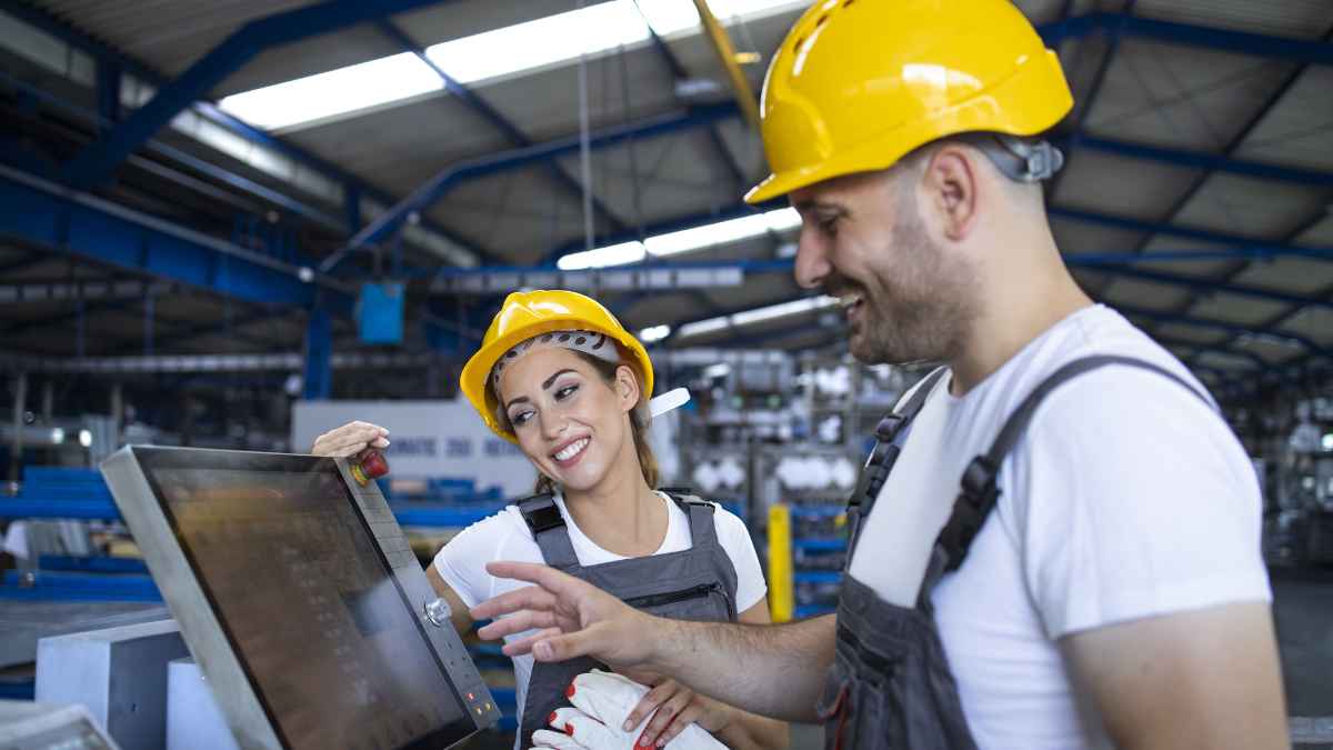 Trabajadores de FP superior usando maquinaria industrial en una fábrica