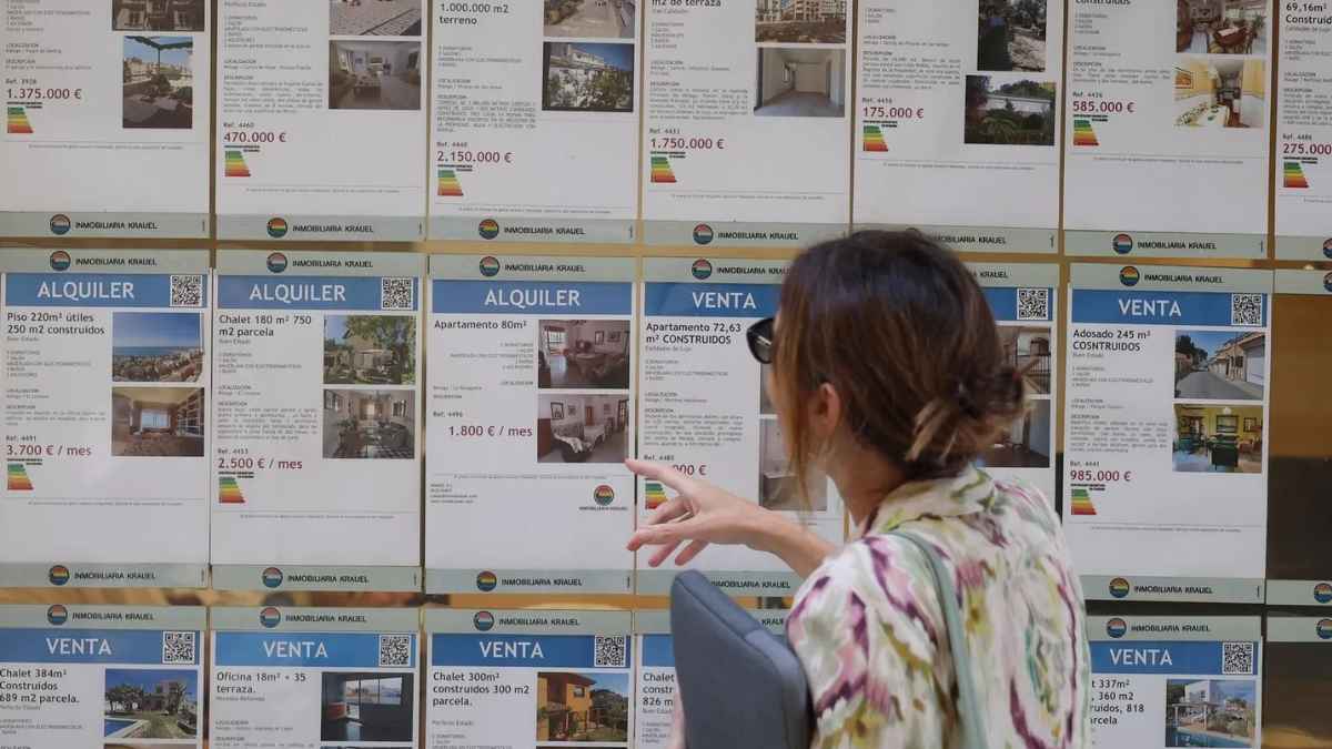 Joven consultando precios de alquiler en escaparate inmobiliario para acceder al Bono Alquiler Joven 2026