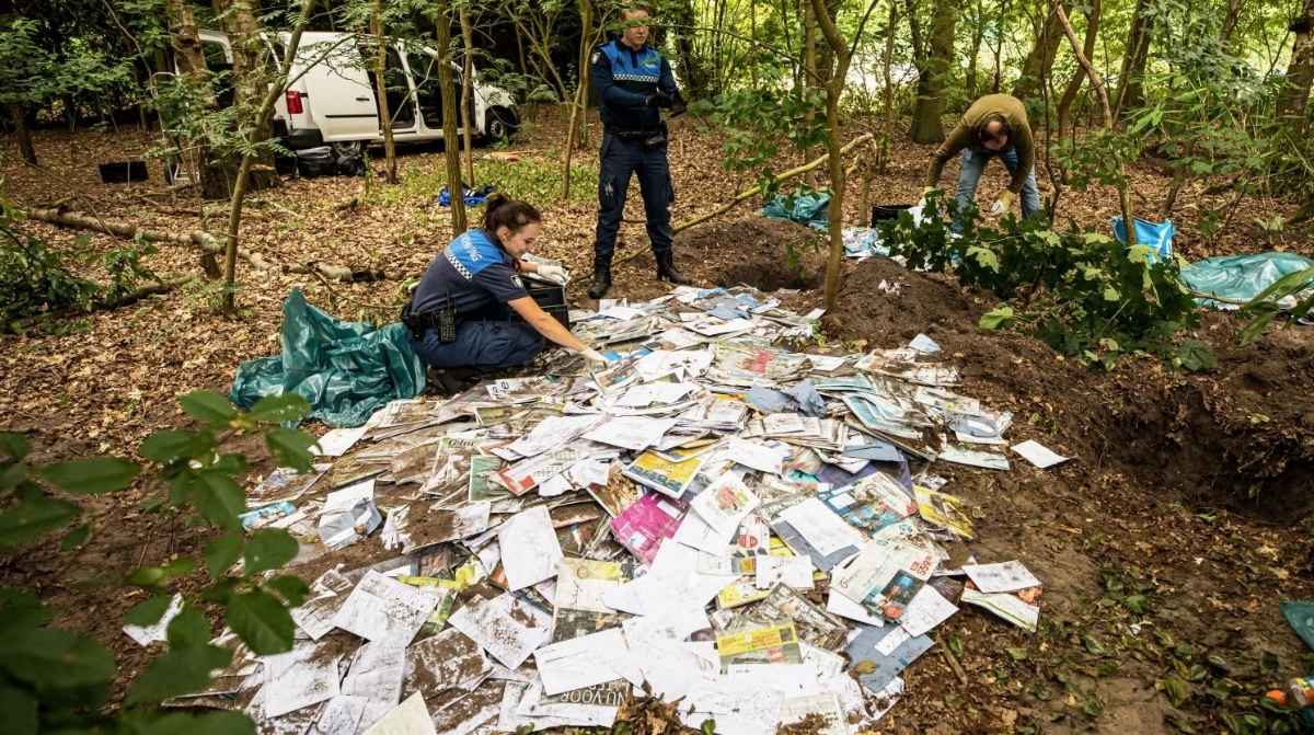 Policía revisando cartas abandonadas en un bosque tras ser tiradas por un cartero interino