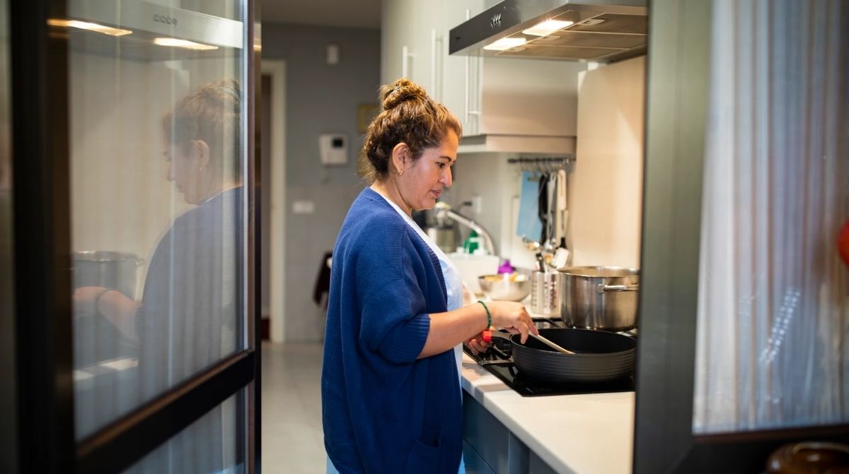 Empleada del hogar cocinando en una vivienda mientras se reclaman inspecciones de trabajo en domicilios