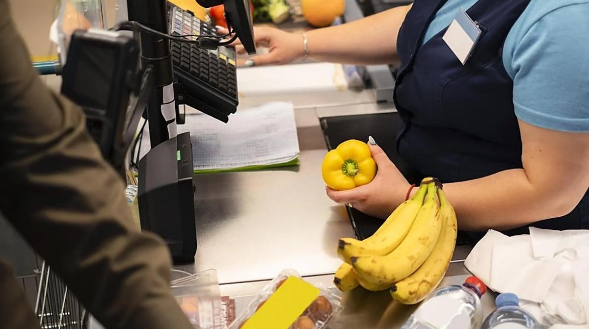 Cajera de supermercado cobrando compra tras permitir uso fraudulento de descuentos a una compañera
