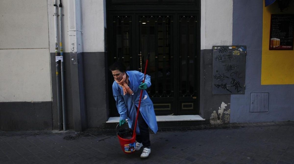empleada de hogar limpiando calle tras despido anulado por ayudar a vecina durante baja por depresión