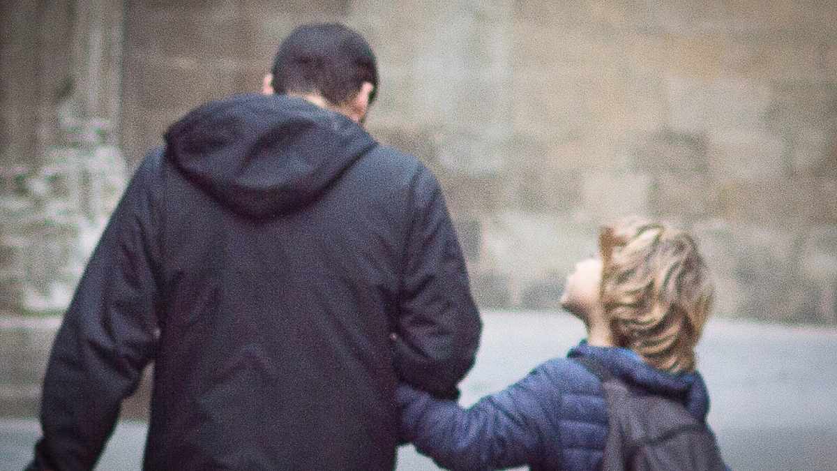 Hijo junto a un adulto en una imagen sobre la pensión de orfandad vitalicia de la Seguridad Social