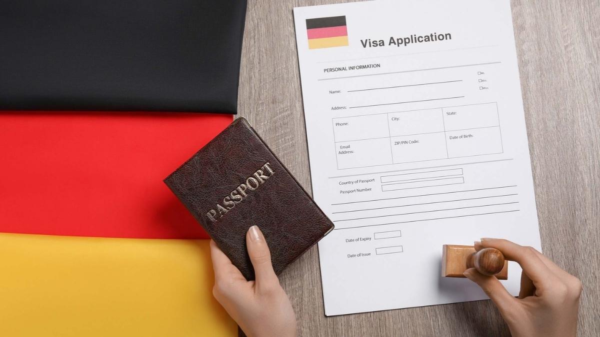 Trabajador revisando documentación para trabajar en Alemania con pasaporte y formulario de solicitud sobre bandera alemana