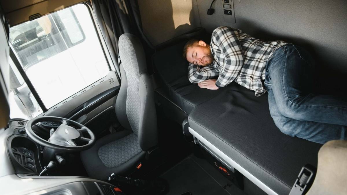 Repartidor tumbado descansando en la cabina de un camión durante su jornada laboral tras ser despedido por la empresa