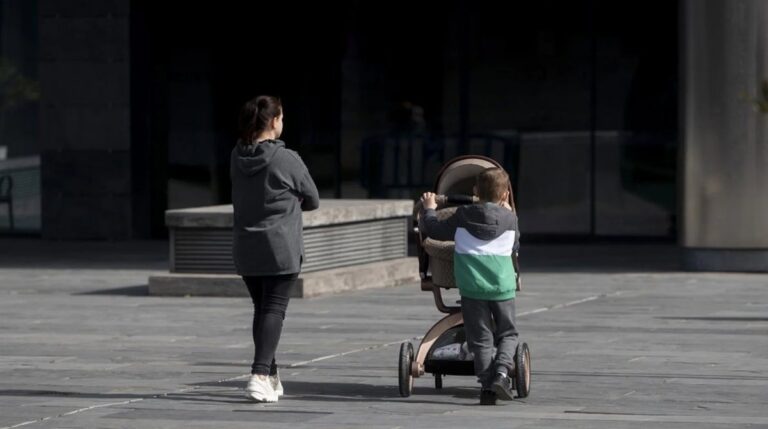 Madre paseando con un bebé en carrito tras la aclaración de la Seguridad Social sobre el permiso por nacimiento hasta los 8 años