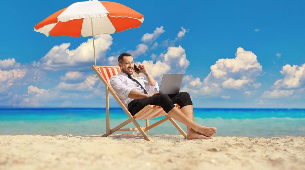 Trabajador disfrutando de sus vacaciones de verano en la playa mientras revisa si los festivos cuentan como días de vacaciones