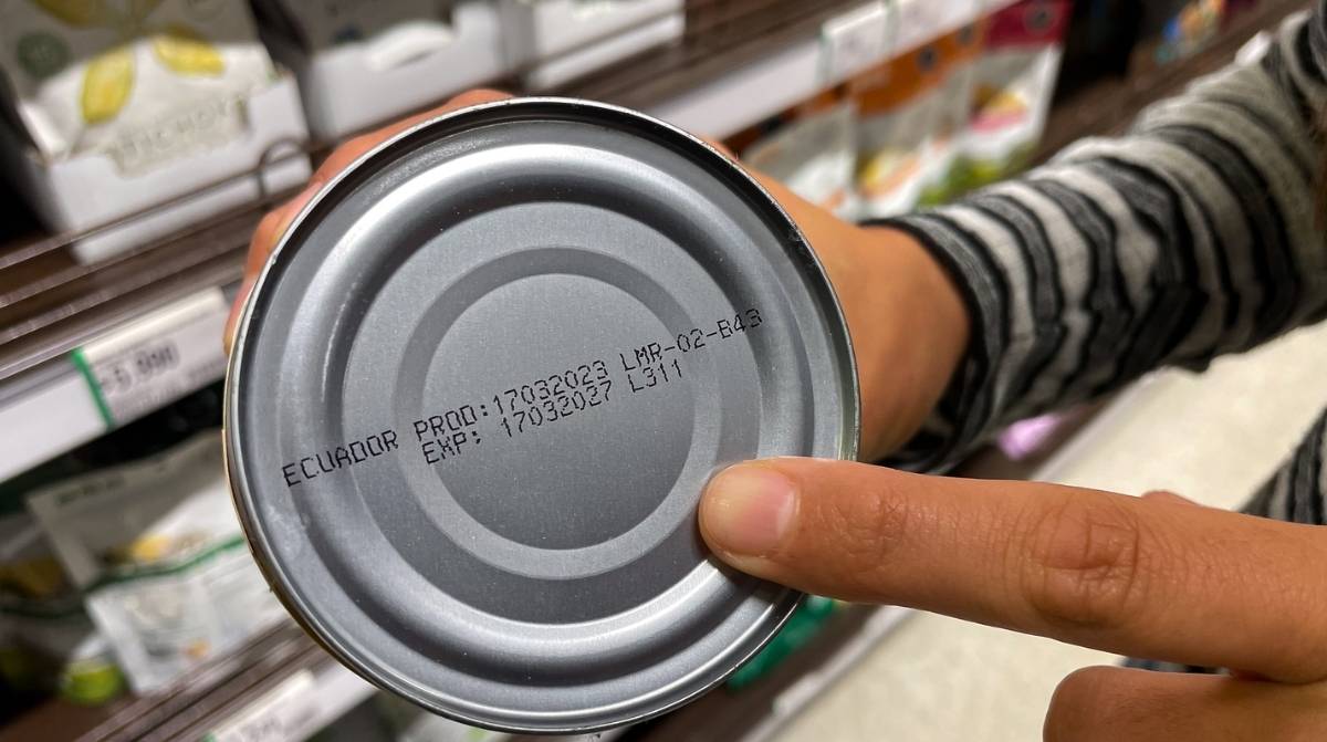 Trabajadora muestra una lata con la fecha de caducidad en un supermercado tras un caso viral en TikTok