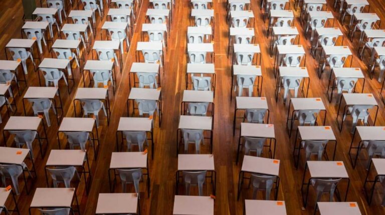 Aula con decenas de mesas preparadas para exámenes de oposiciones con miles de plazas de empleo público en 2026