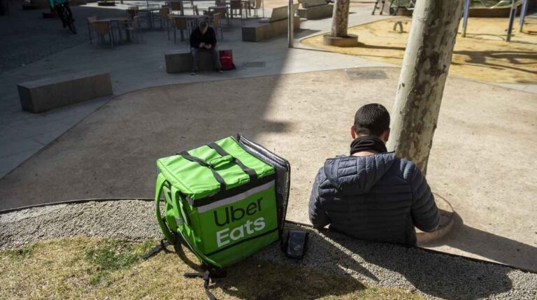 Trabajador de Uber Eats sentado junto a una mochila de reparto tras un despido declarado improcedente por la justicia