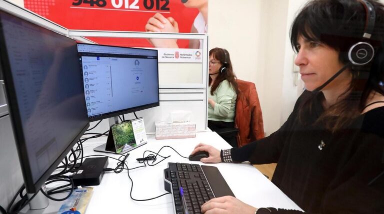 Trabajadora de atención al cliente atendiendo llamadas telefónicas en una oficina tras la nueva ley que limita las esperas a tres minutos