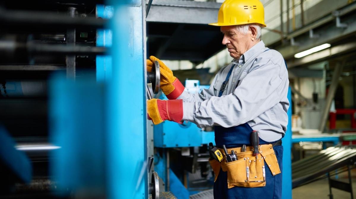 Trabajador de edad avanzada operando maquinaria industrial en una fábrica ante el debate sobre retrasar la jubilación hasta los 73 años