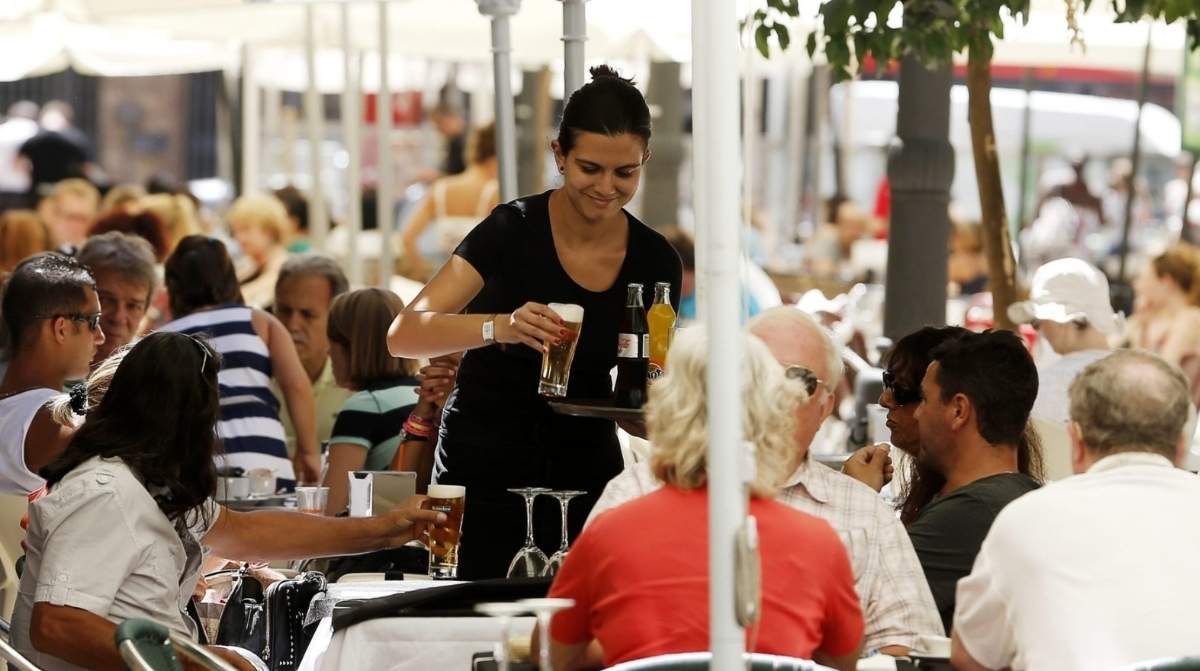 Camarera atendiendo a clientes en un bar con nueva normativa de audiencia previa antes del despido