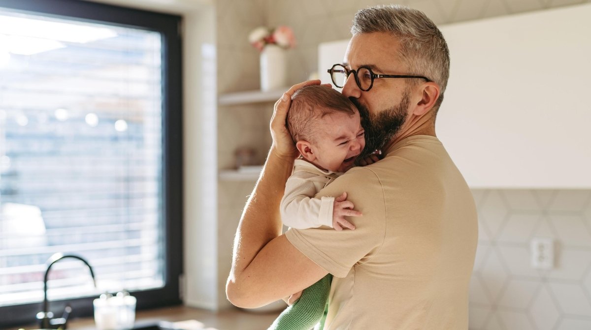 Padre cuidando a un bebé en casa tras la reducción de jornada laboral para padres con hijos menores de 12 años
