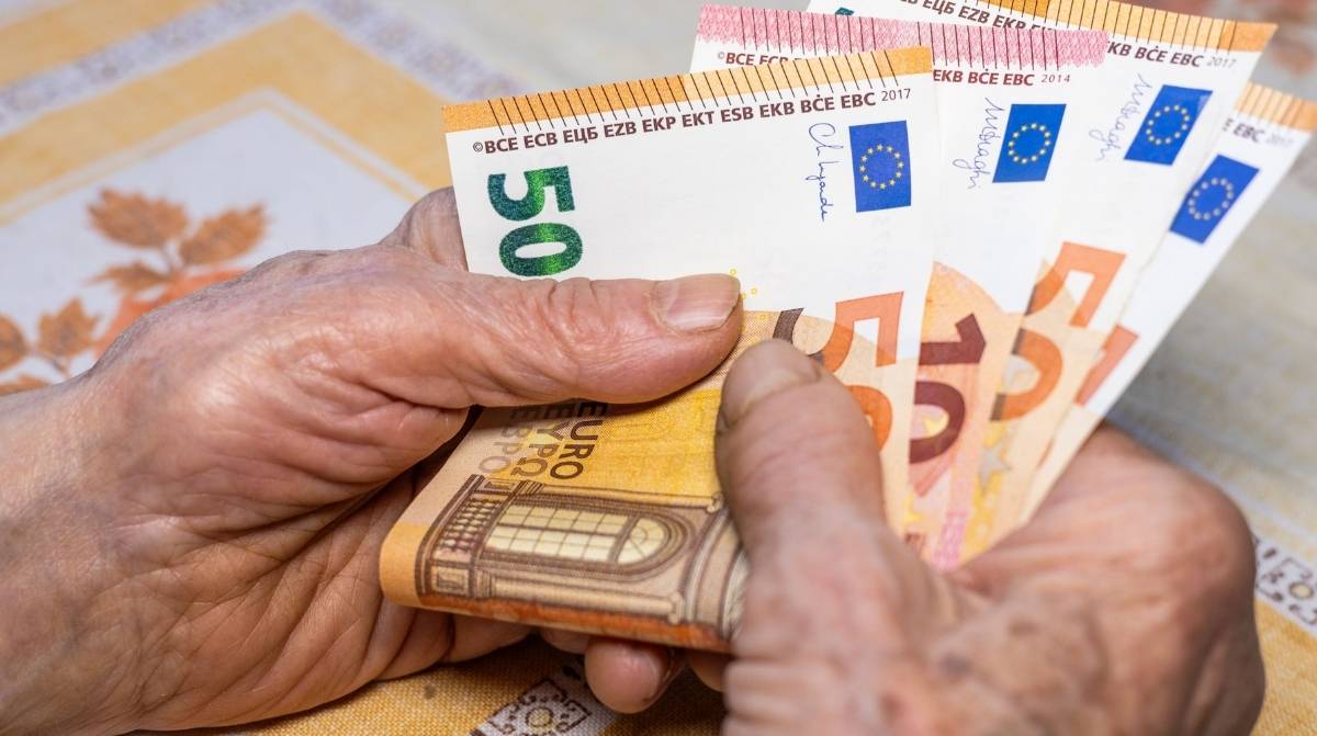 Persona mayor sujetando billetes de euro relacionados con la pensión no contributiva del Imserso