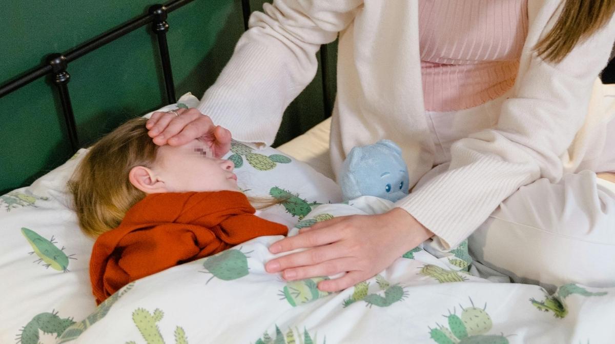 niño enfermo en cama cuidado por familiar permiso retribuido cinco dias
