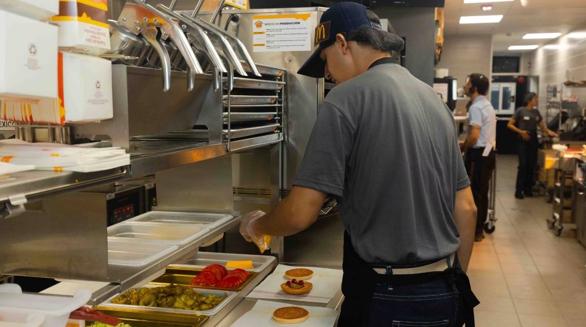 Trabajador de comida rápida preparando alimentos en cocina tras subida salarial por convenio