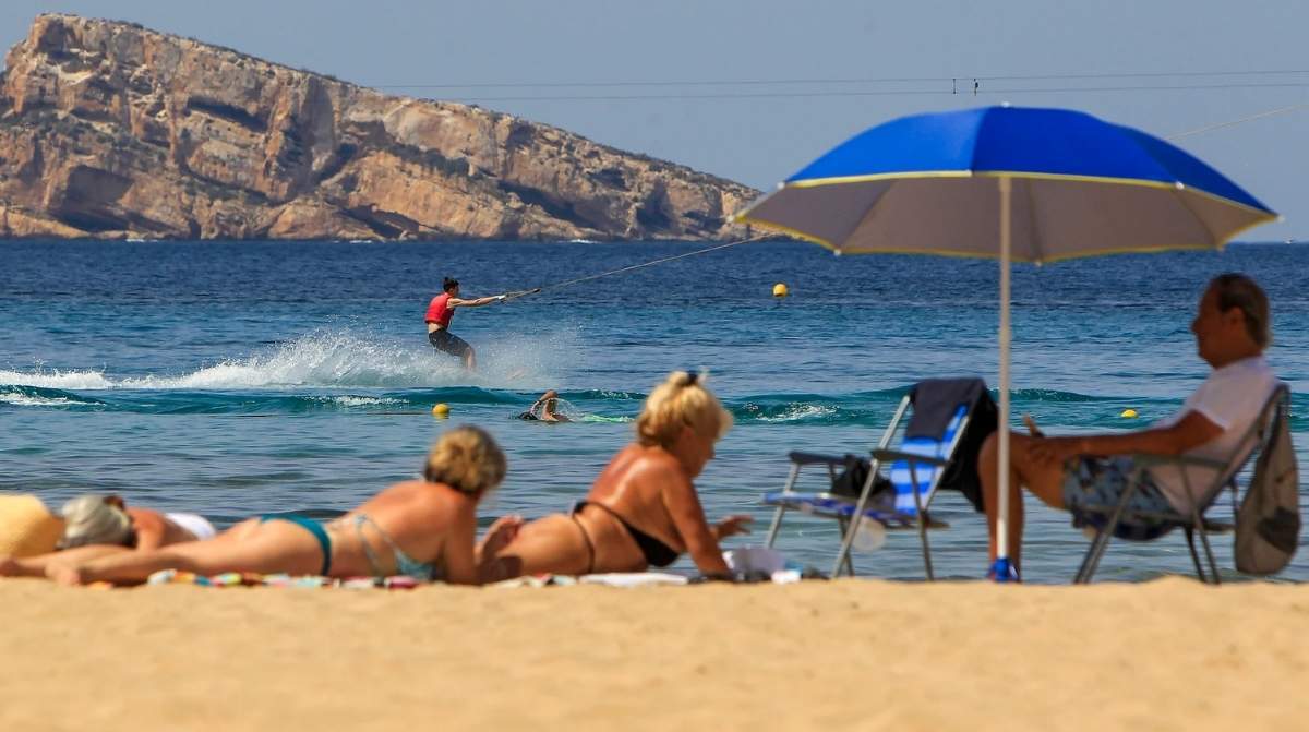 trabajadores disfrutando de vacaciones en la playa en España reflejando cambio hacia más descanso laboral