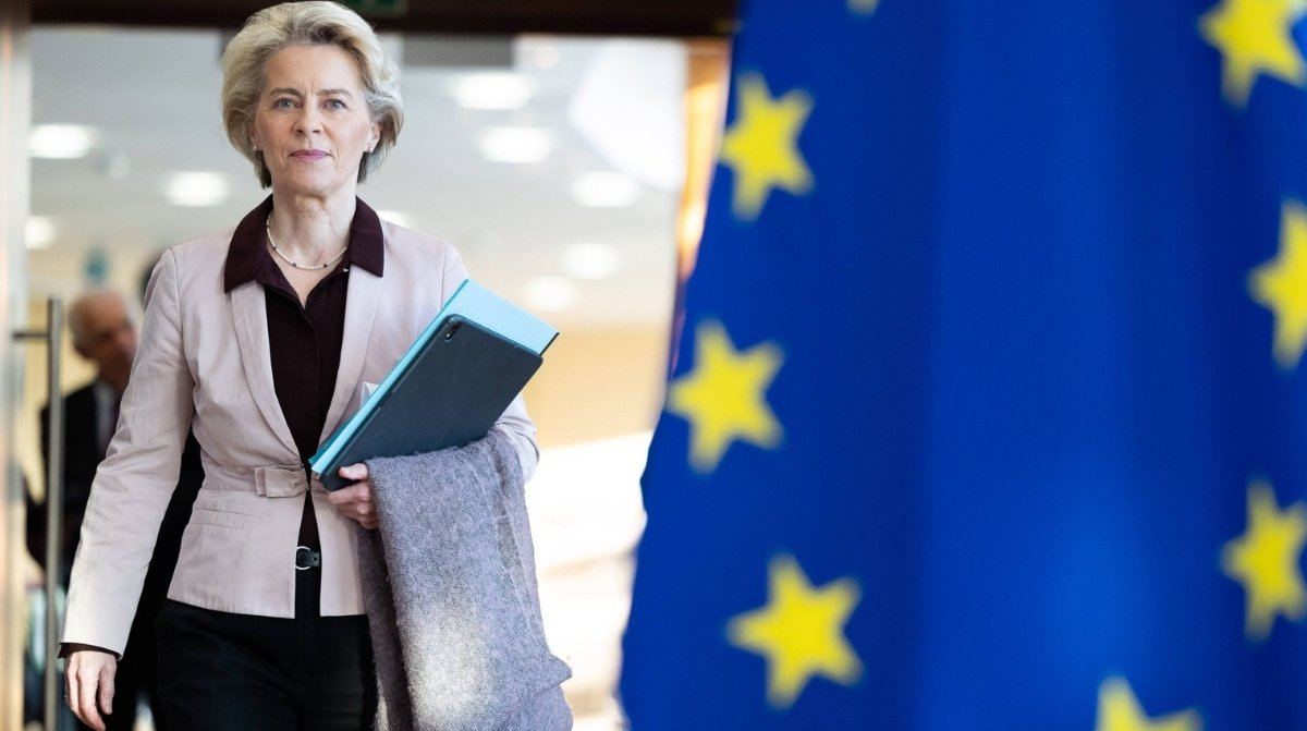 Representante de la Unión Europea junto a bandera europea sobre nuevas normas para restringir ayudas sociales a desempleados
