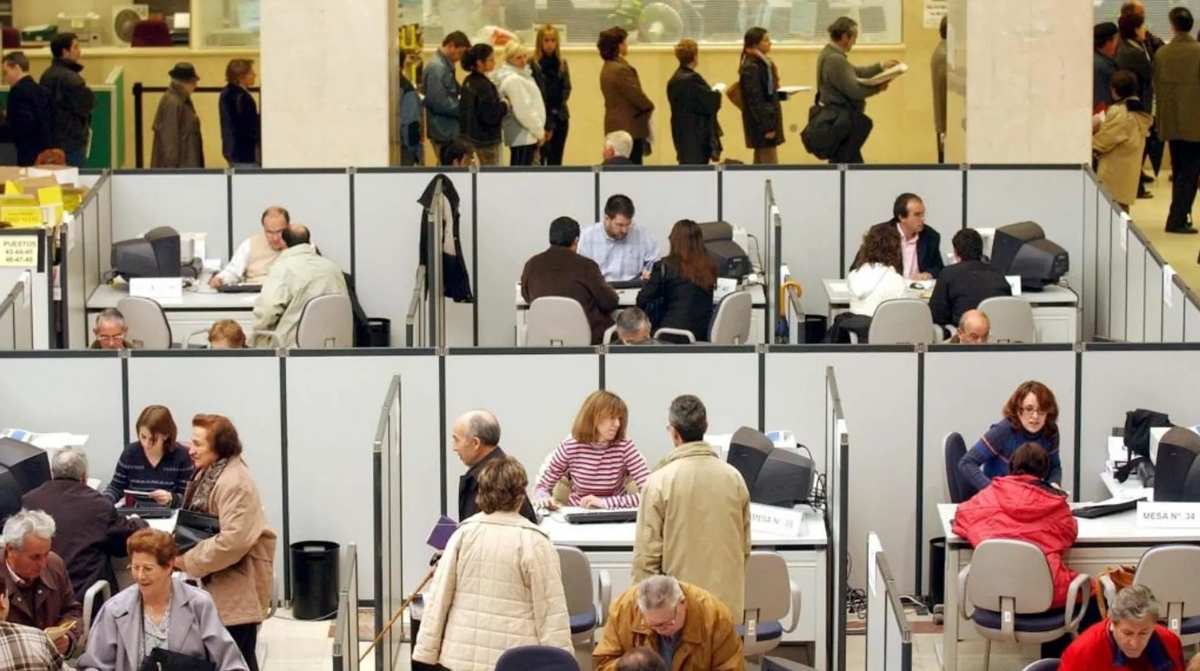 Funcionarios y ciudadanos realizando trámites en una oficina de la Administración del Estado