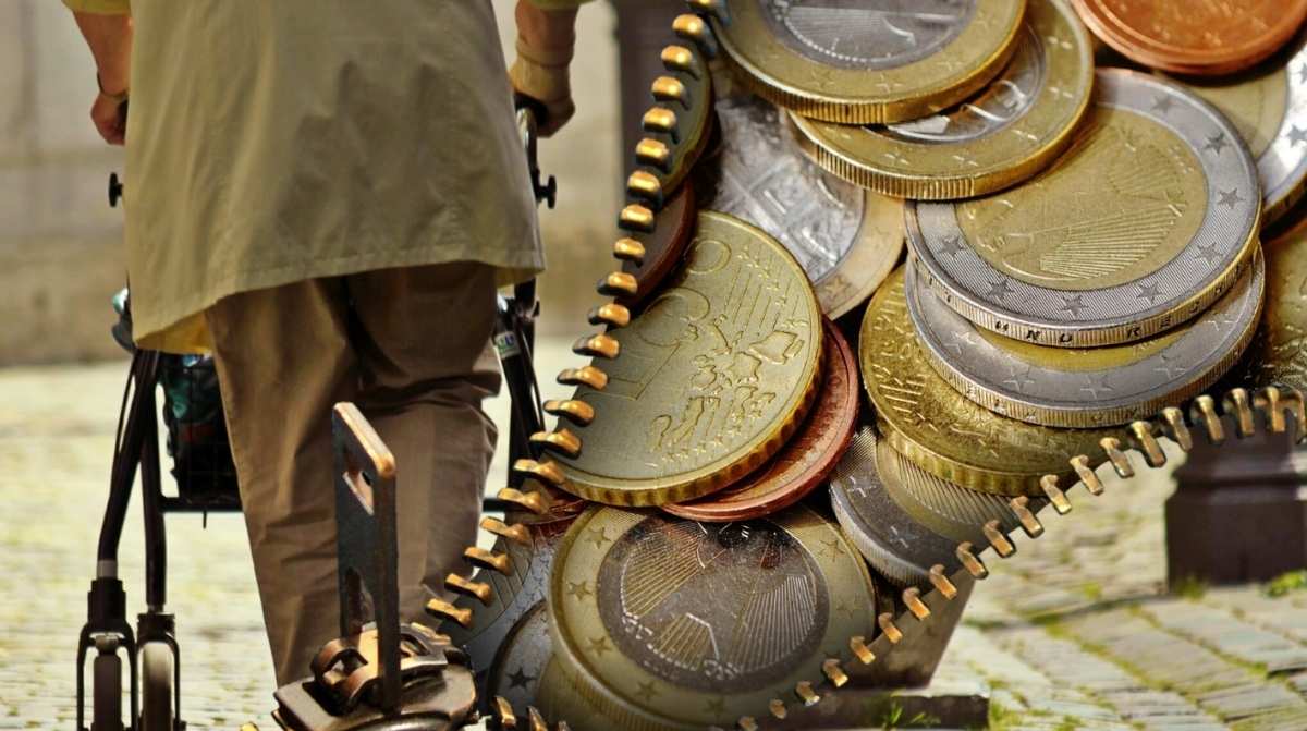 Persona jubilada con andador junto a monedas de euro en una imagen sobre el cobro de dos pensiones de jubilación de la Seguridad Social