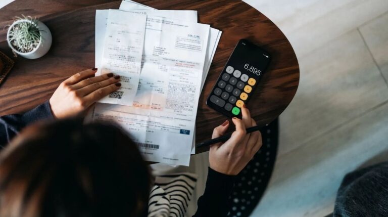Persona revisando facturas y calculando gastos para solicitar la prórroga de la tarifa plana de autónomos