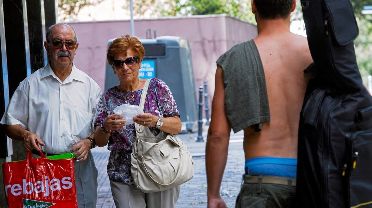 Hombre paseando sin camiseta por una calle mientras varias ciudades españolas imponen multas de hasta 750 euros.