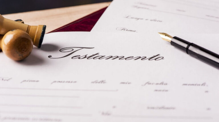 Testamento junto a un sello notarial y una pluma sobre un documento de herencia