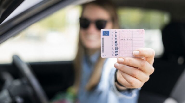 Joven mostrando el reverso del carnet de conducir desde el coche tras obtener el permiso B