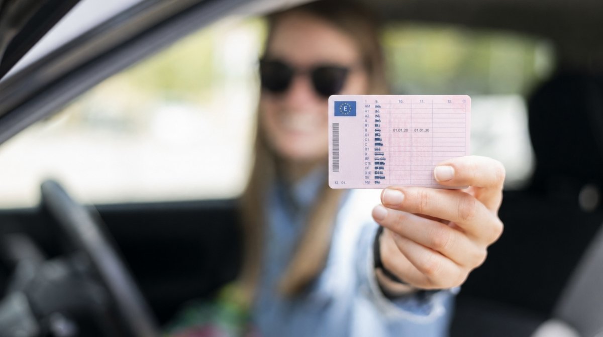 Joven mostrando el reverso del carnet de conducir desde el coche tras obtener el permiso B