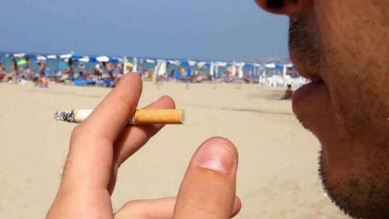 Persona fumando un cigarrillo en una playa de Barcelona donde algunos municipios imponen multas de hasta 750 euros