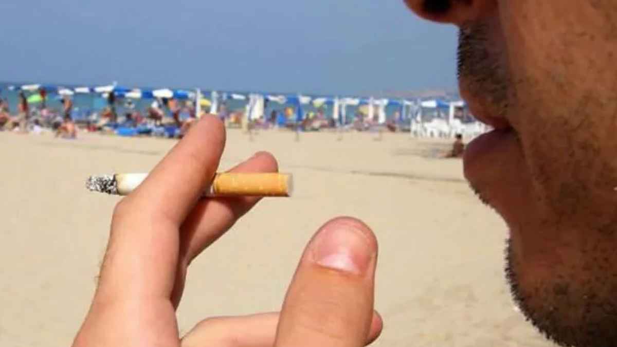 Persona fumando un cigarrillo en una playa de Barcelona donde algunos municipios imponen multas de hasta 750 euros