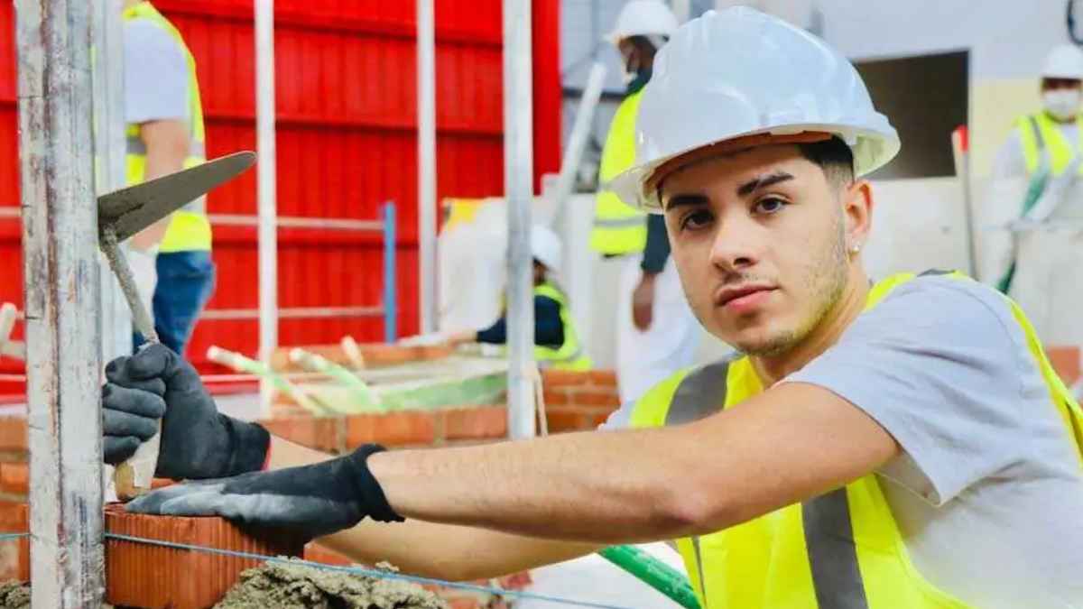 Joven aprendiz de obra trabajando como albañil en una construcción