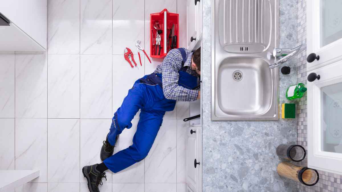 Fontanero trabajando bajo el fregadero de una cocina durante una reparación en una vivienda