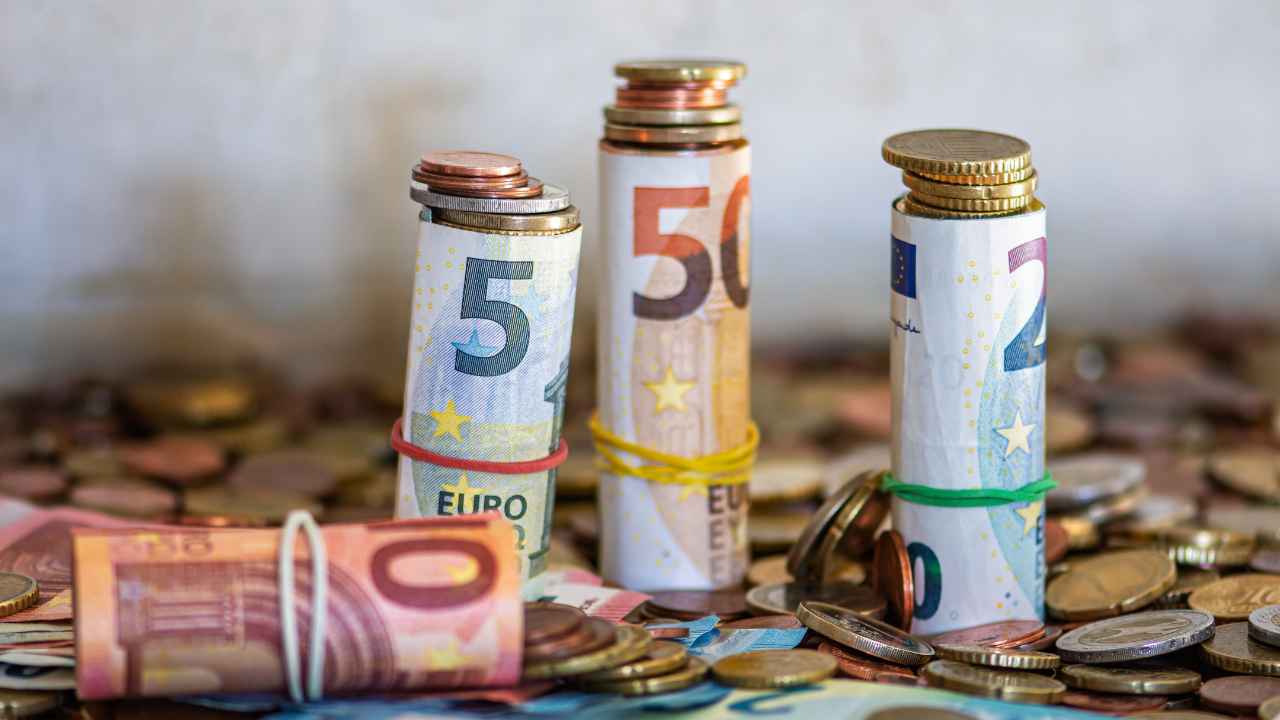 Billetes y monedas en euros que ilustran la ayuda de hasta 115 euros por hijo de la Seguridad Social para familias con menores.