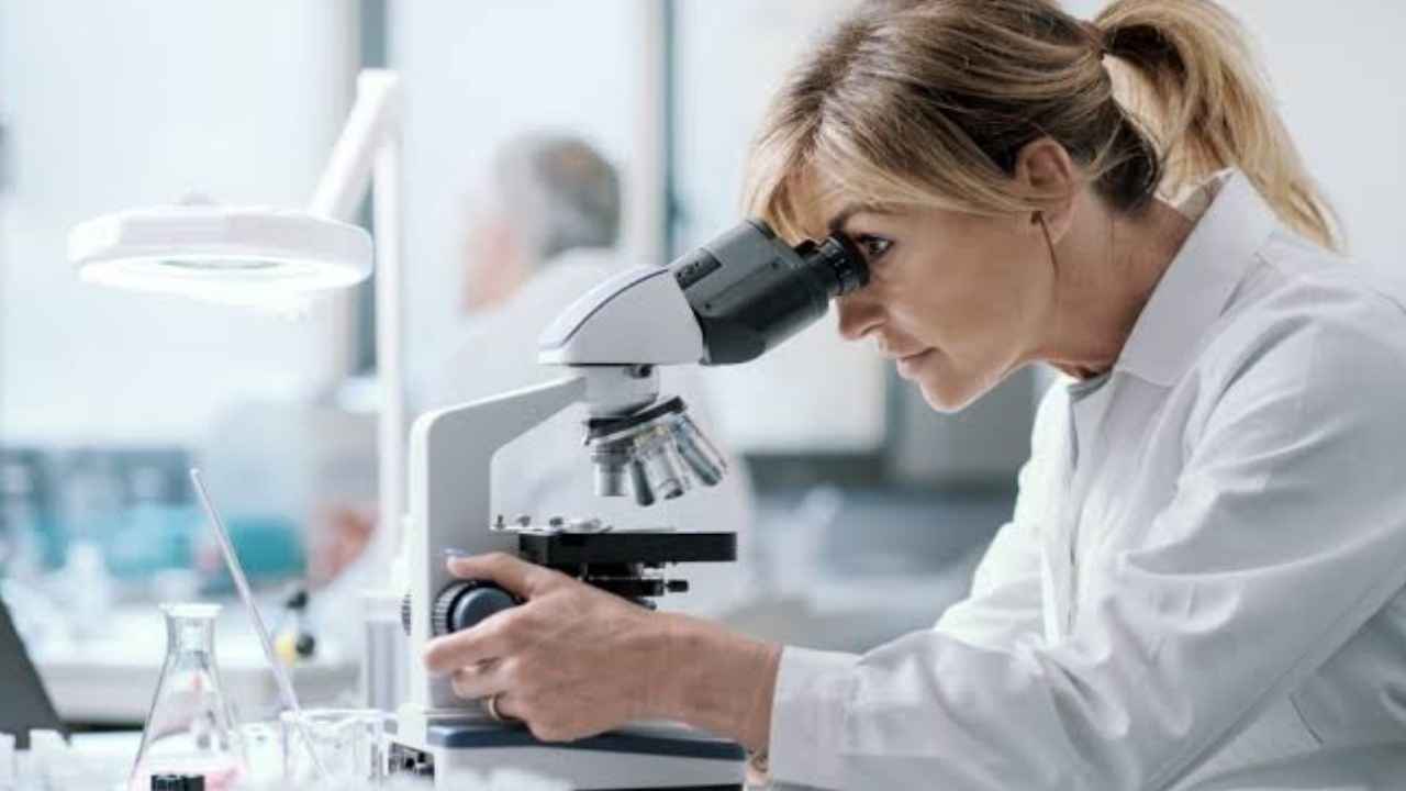 Infoemplea2 14 Investigadora observa una muestra con un microscopio en un laboratorio de investigación sanitaria