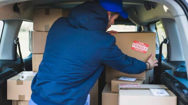 Trabajador cargando cajas en el maletero de un vehículo