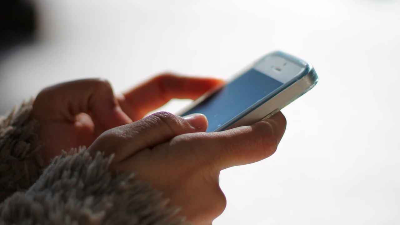 Persona utilizando un teléfono móvil para consultar mensajes de WhatsApp