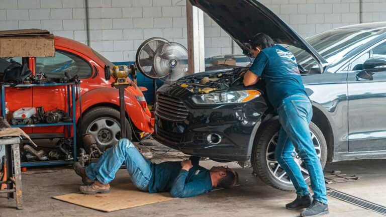Dos mecánicos reparan un coche en un taller de automoción