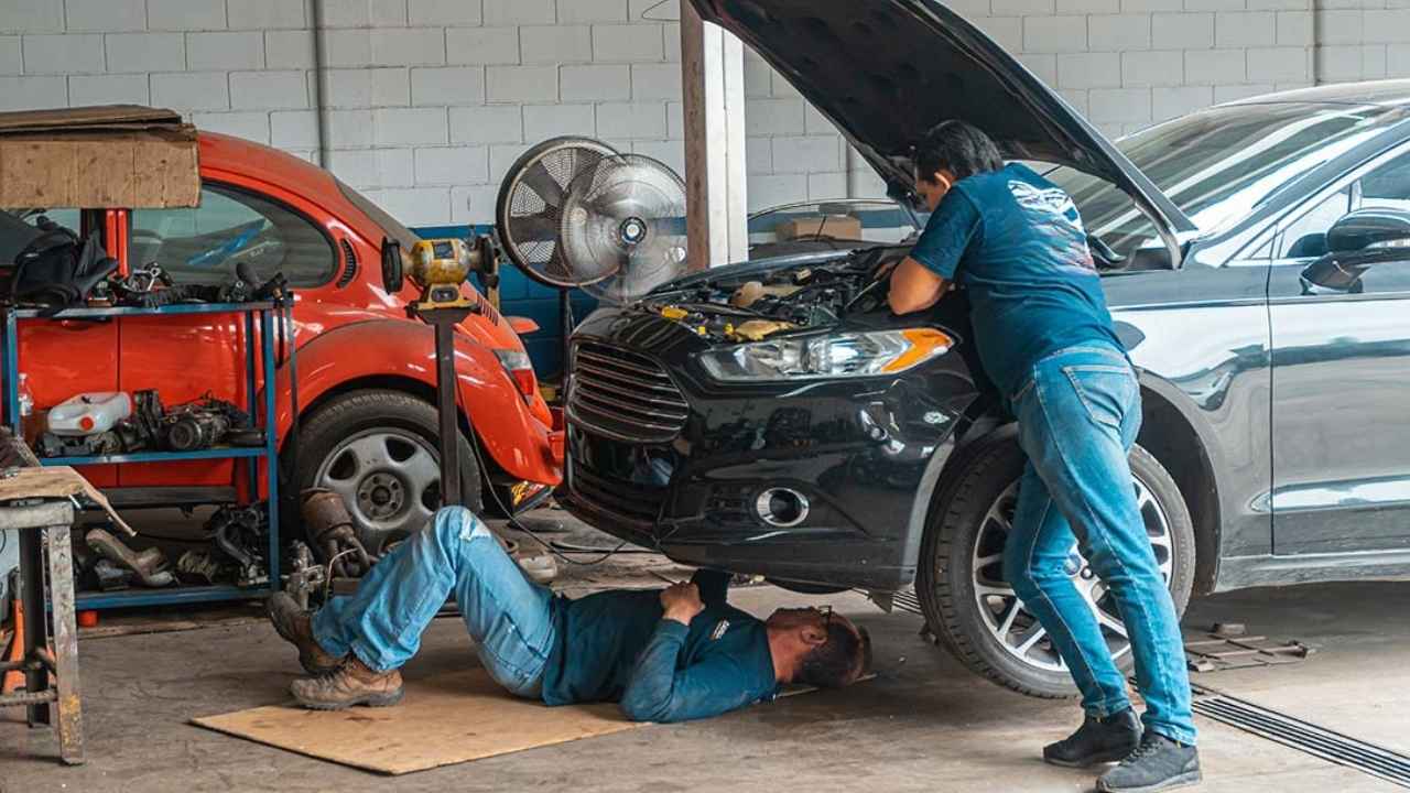 Dos mecánicos reparan un coche en un taller de automoción
