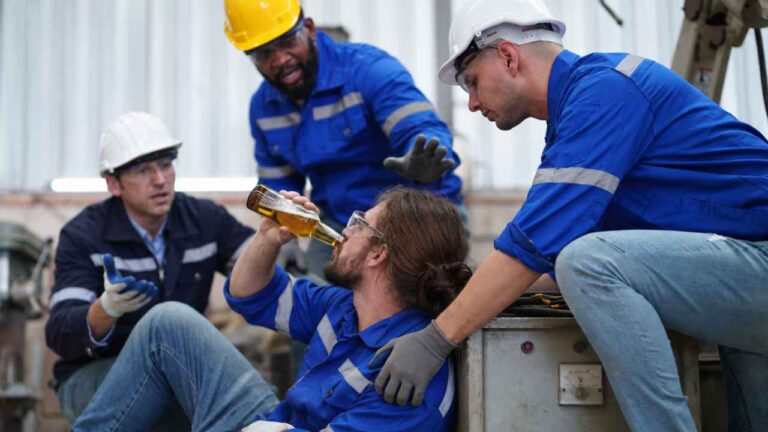 Trabajador bebiendo cerveza en una obra junto a varios compañeros