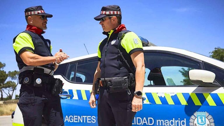 Dos Agentes de Movilidad de Madrid junto a un vehículo oficial