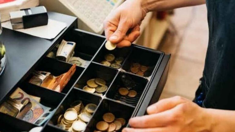 Trabajadora manipulando dinero en una caja registradora de un comercio
