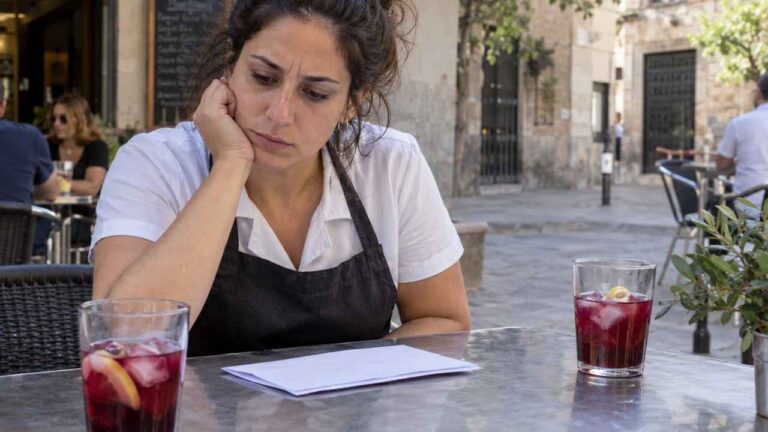 Camarera sentada en una terraza junto a dos tintos de verano durante una baja médica