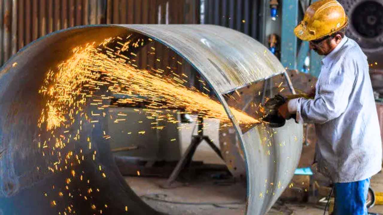 Trabajador del sector del metal trabajando sobre una gran pieza de acero en una nave industrial