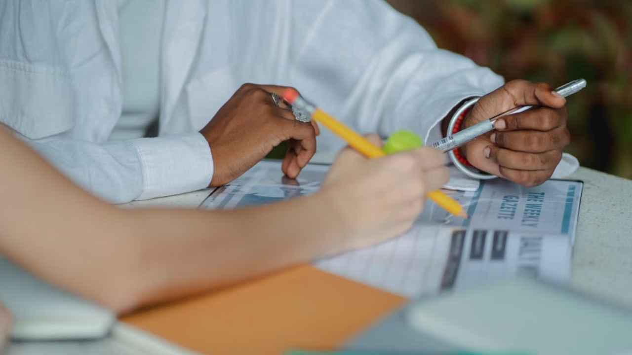 Estudiantes toman apuntes y preparan un trabajo en grupo.