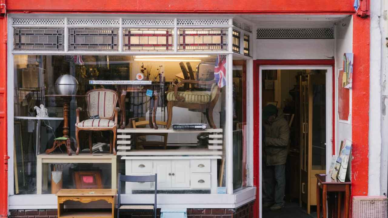 Escaparate de una tienda con muebles expuestos junto a la acera.