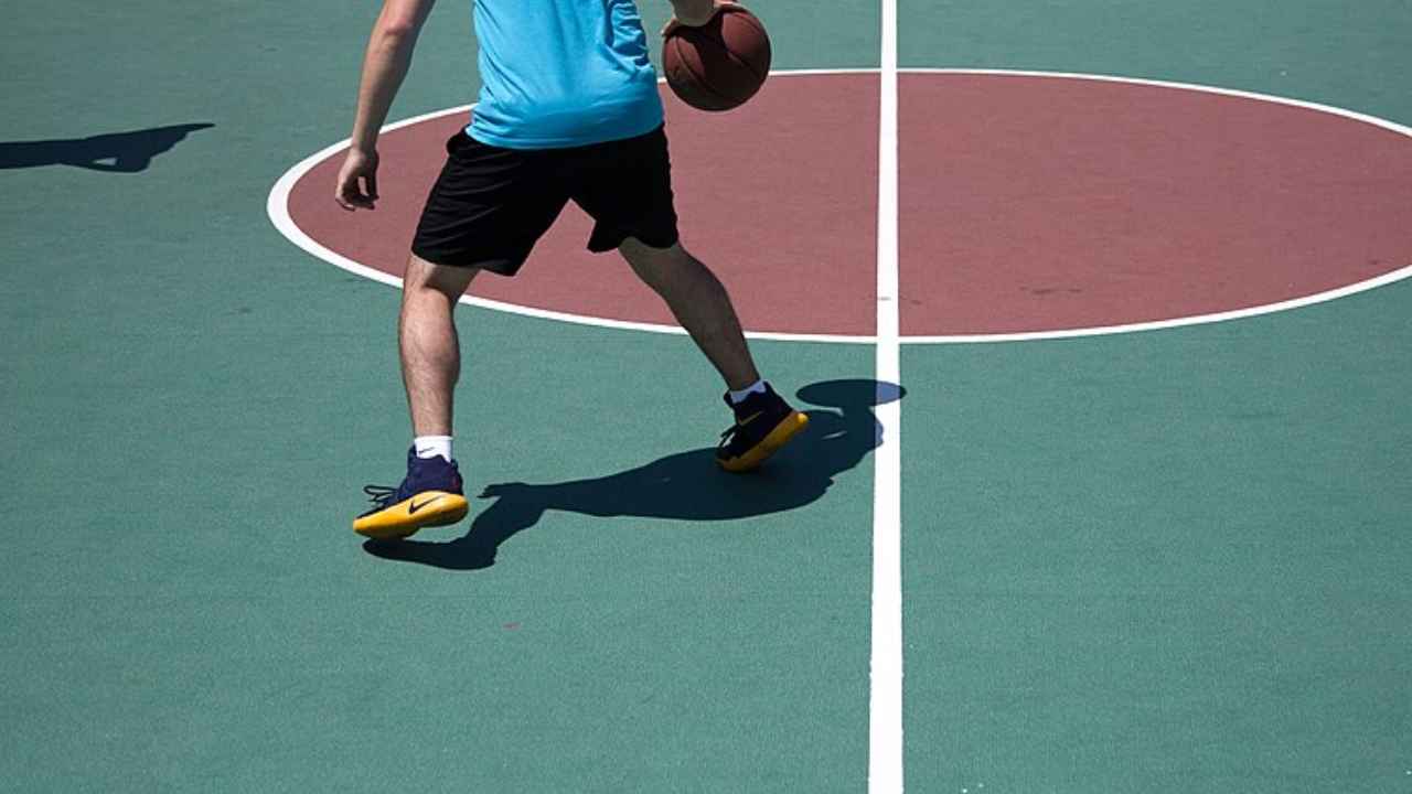 Persona botando un balón de baloncesto en una pista